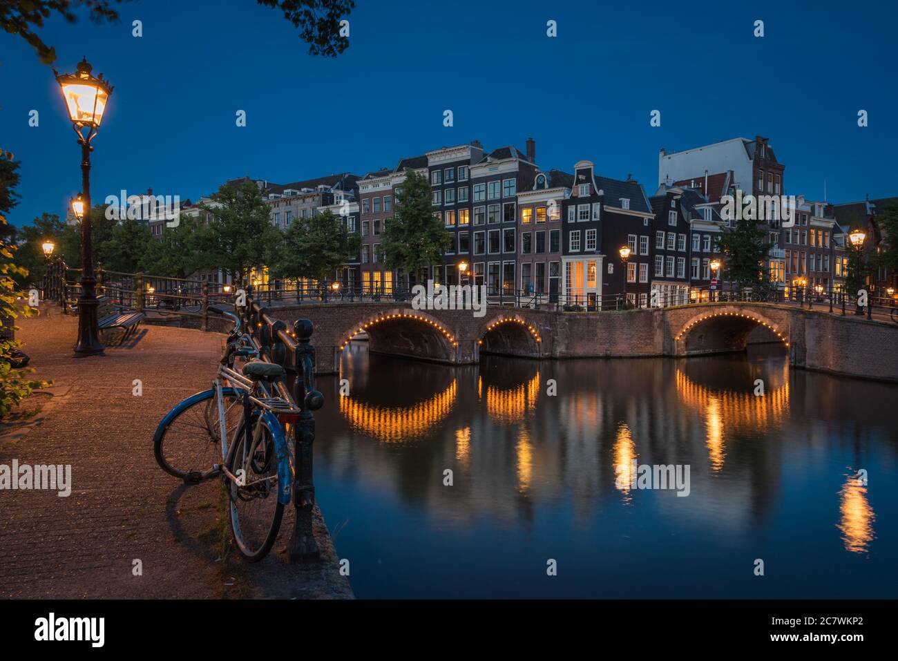Le vélo solitaire à côté des canaux la nuit dans l'illuminé Amsterdam, pays-Bas Banque D'Images
