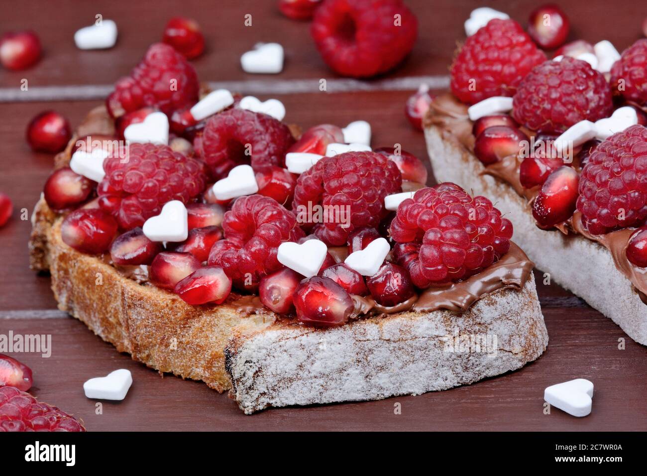Deux tranches de pain au chocolat et à la framboise sur une table en bois brun Banque D'Images