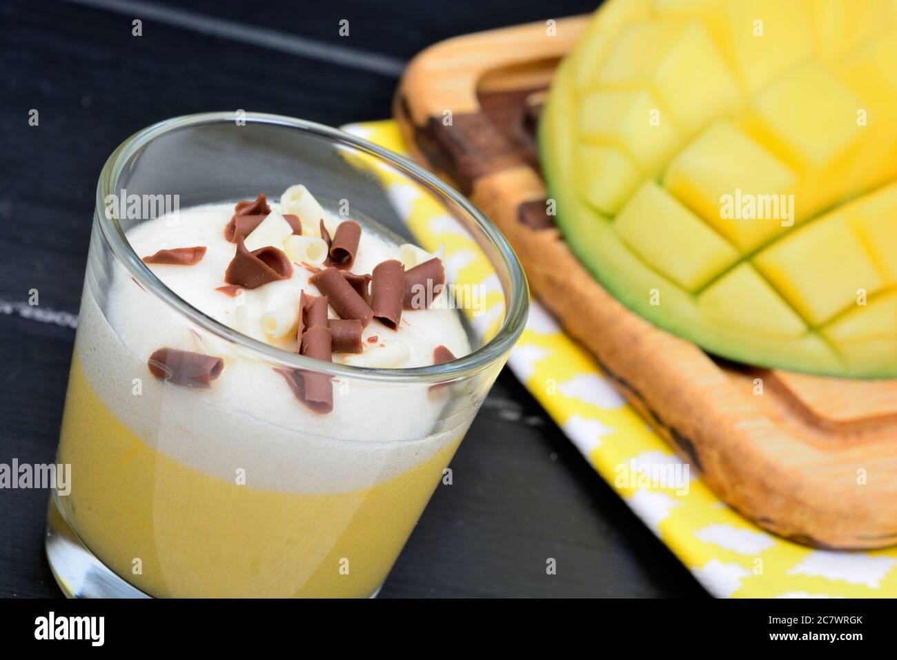 Mousse de mangue à la crème fouettée et au chocolat dans un pot en verre sur table en bois noir Banque D'Images