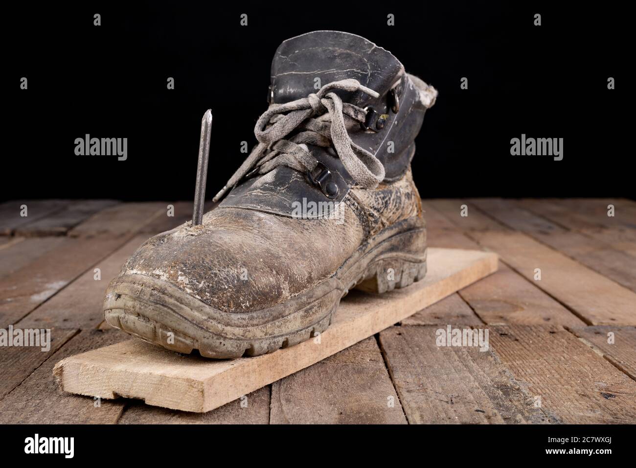 Ancienne chaussure de travail percée d'un clou. Un accident de travail lors  de la rénovation d'une maison. Arrière-plan sombre Photo Stock - Alamy