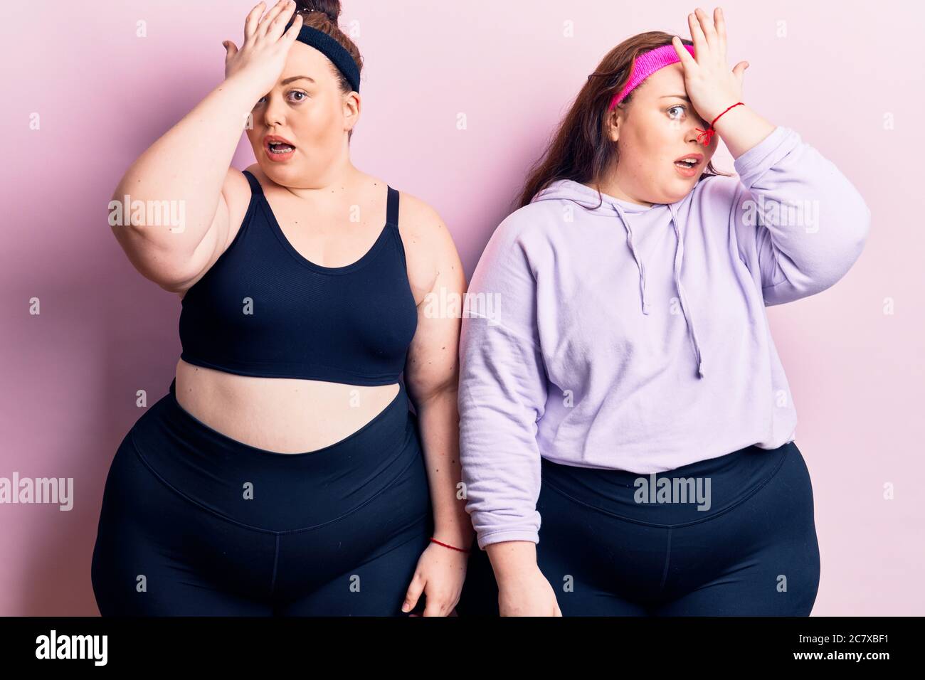 Jeunes jumeaux de taille plus portant des vêtements de sport surpris de la main sur la tête pour l'erreur, souvenez-vous erreur. oublié, mauvais concept de mémoire. Banque D'Images Jeunes jumeaux de taille plus portant des vêtements de sport surpris de la main sur la tête pour l'erreur, souvenez-vous erreur. oublié, mauvais concept de mémoire. Banque D'Images