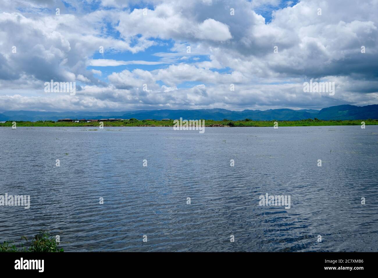Le lac Inle coule sous un ciel bleu ensoleillé avec des nuages blancs. Grand angle et horizontal. Dans l'État Shan du Myanmar Banque D'Images