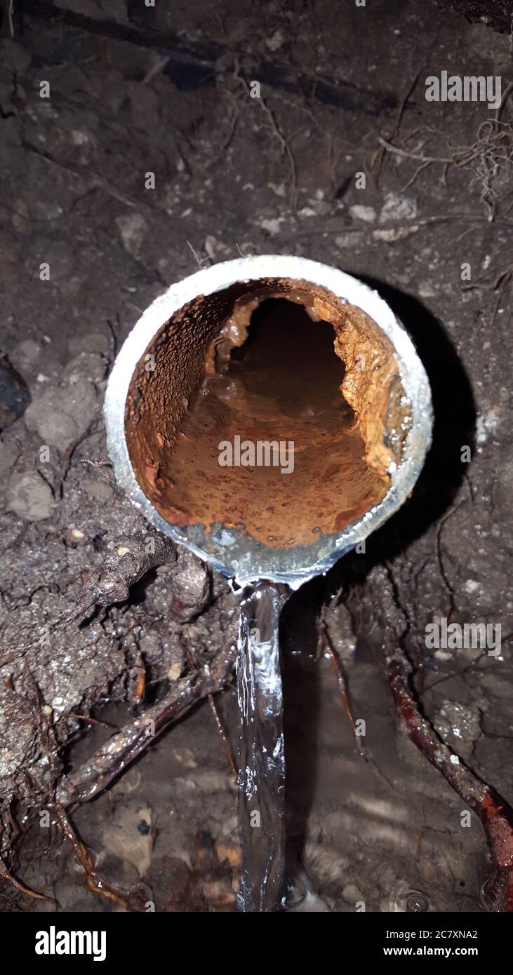 Vieux tuyau d'eau rouillé cassé sous terre avec de l'eau courante pendant  l'extérieur Photo Stock - Alamy