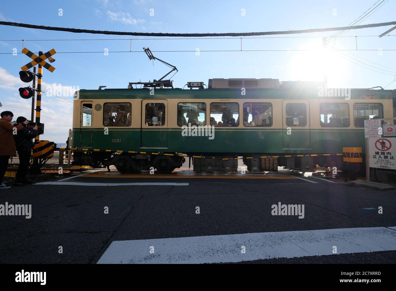 Train du chemin de fer électrique Enoshima passant par le passage à niveau près de la gare de Kamakurakokomae. Sous le ciel bleu ensoleillé. Banque D'Images
