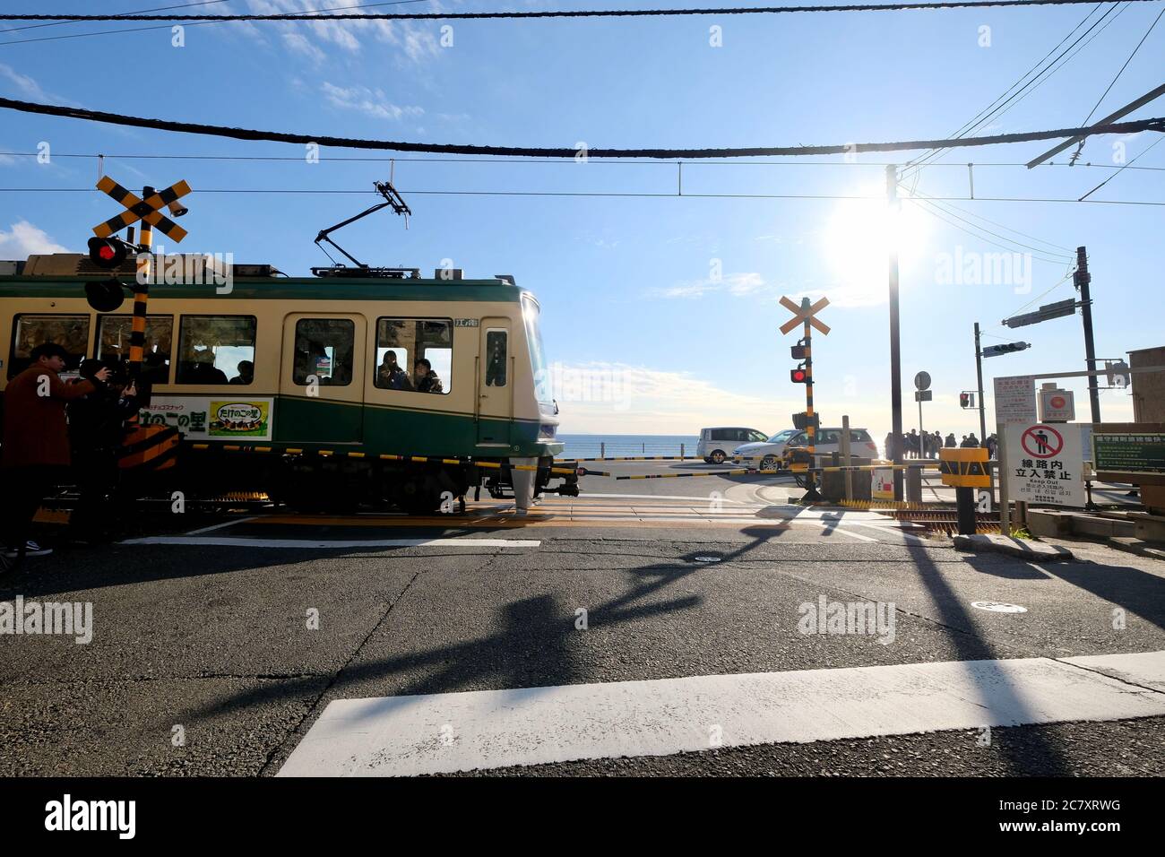 Train du chemin de fer électrique Enoshima passant par le passage à niveau près de la gare de Kamakurakokomae. Sous le ciel bleu ensoleillé. Banque D'Images