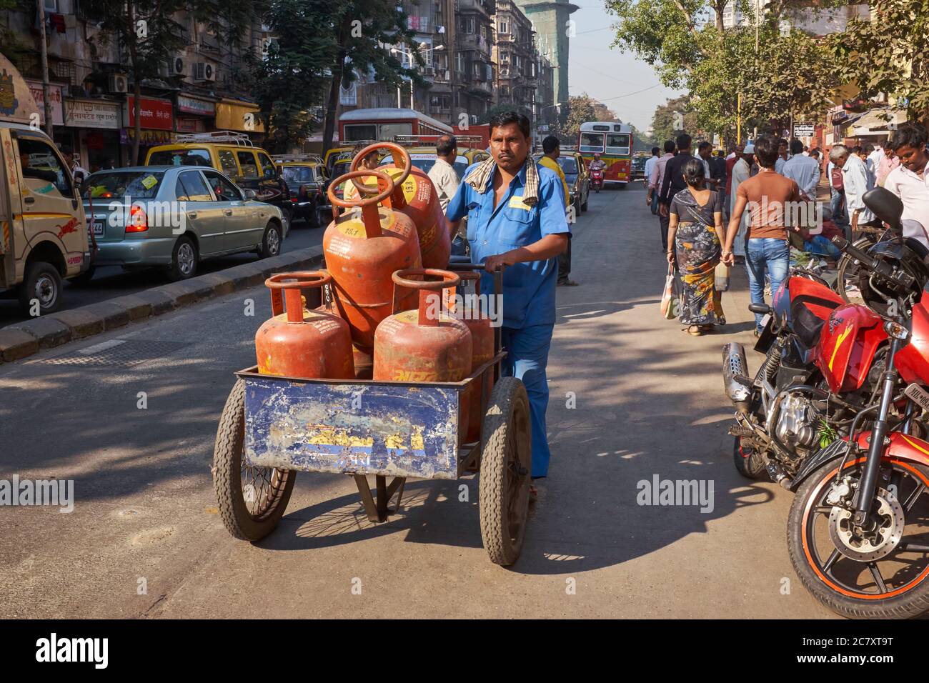 Les bouteilles de gaz de cuisson sont transportées sur une chathart par un employé de compagnie de gaz le long d'une route à Mumbai, Inde Banque D'Images