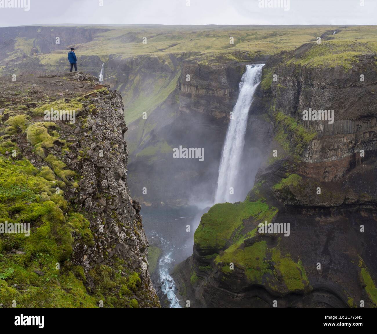 Vallée de la rivière Fossa avec la belle cascade de Haifoss en Islande du Sud avec homme dans la veste bleue debout sur la falaise et regardant la vue Banque D'Images