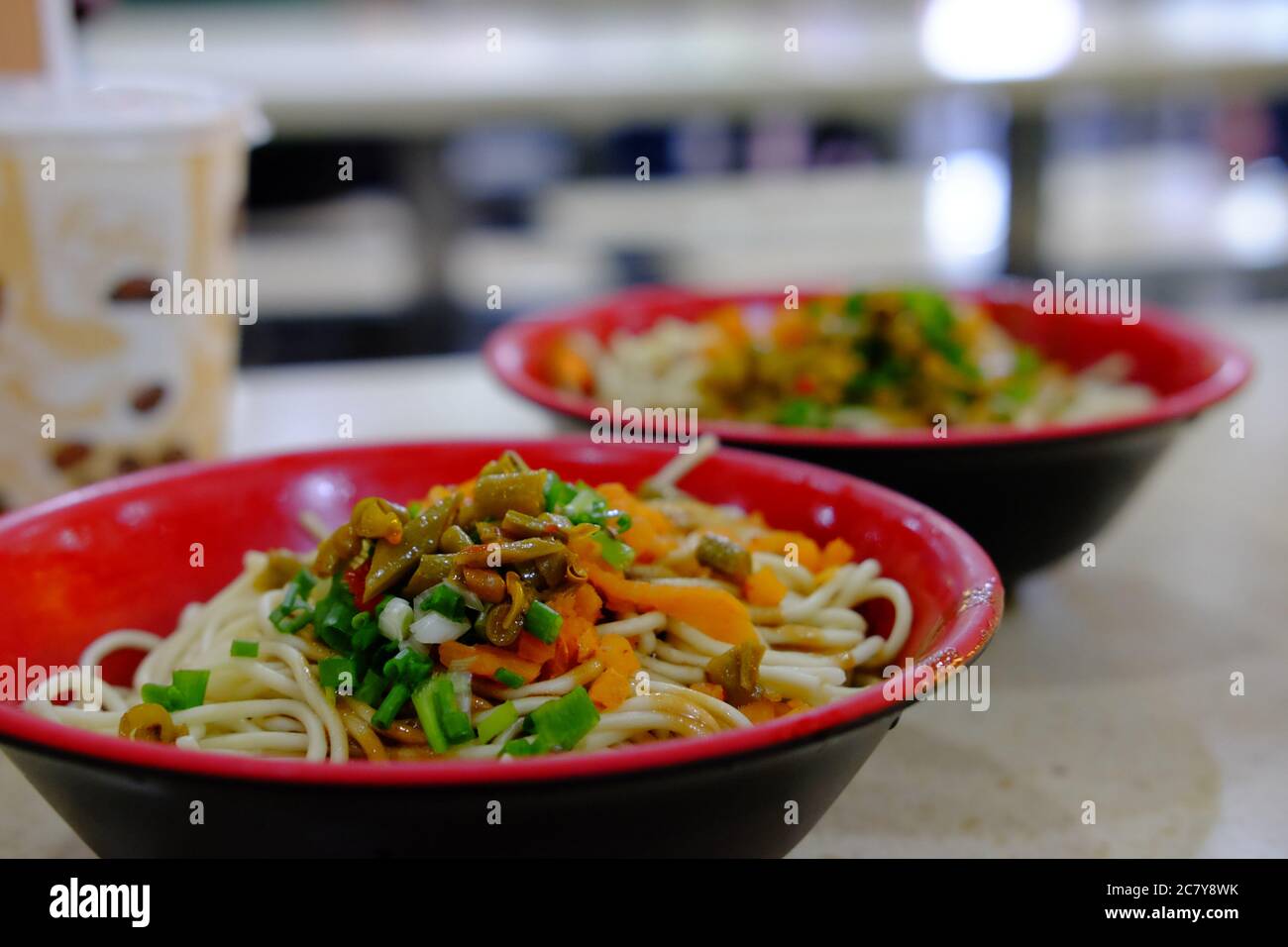 fermez les nouilles chaudes et sèches avec de la pâte de sésame dans des bols rouges. Petit déjeuner traditionnel populaire de Wuhan Hubei Chine. Arrière-plan flou Banque D'Images