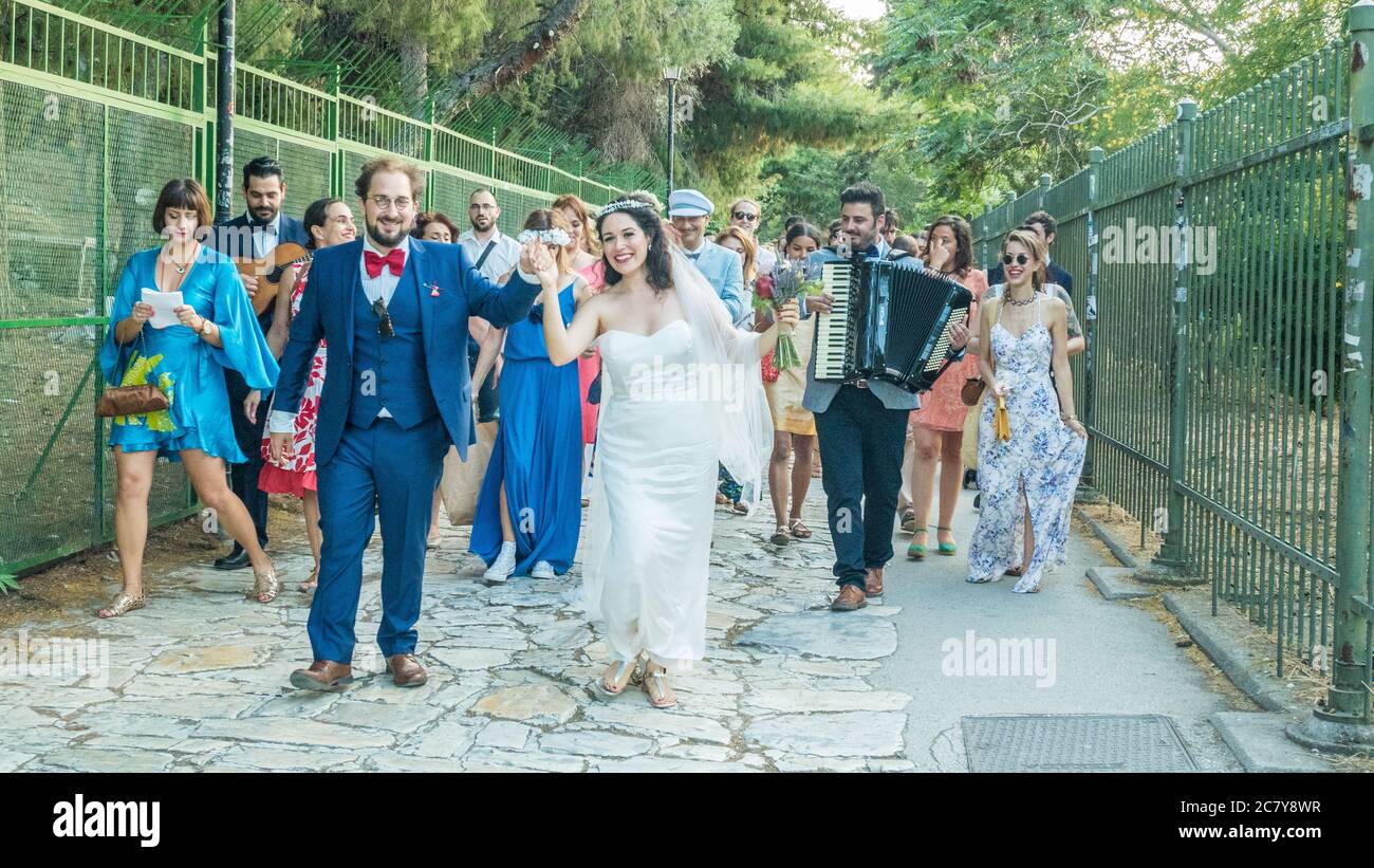 Joyeux mariage souriant jouant des instruments de musique marcher sur une route à Athènes, Grèce Banque D'Images