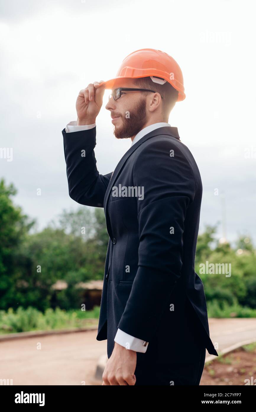 Beau, jeune ingénieur, contremaître, architecte-constructeur se penche sur la construction de la structure, à la gare, le port d'un casque de protection blanc, sm Banque D'Images