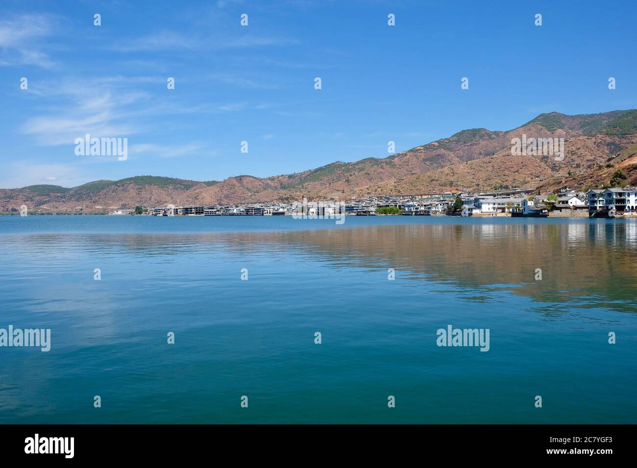 Montagnes et maisons d'auberge le long du lac bleu d'Erhai à Shuanglang Yunnan Chine. Réflexion symétrique dans l'eau paisible. Banque D'Images