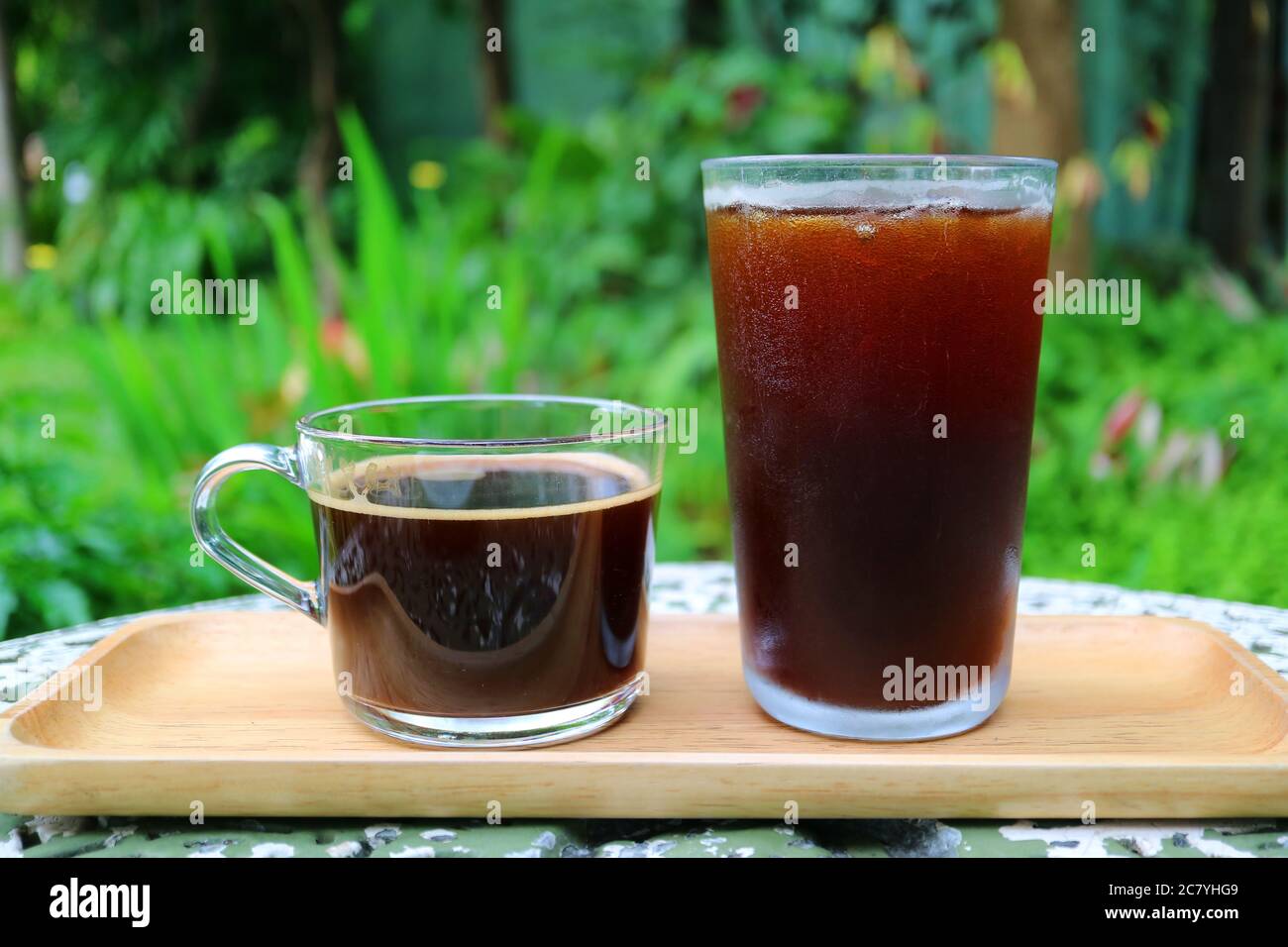 Café chaud et café glacé sur un plateau en bois servi sur une table de jardin Banque D'Images