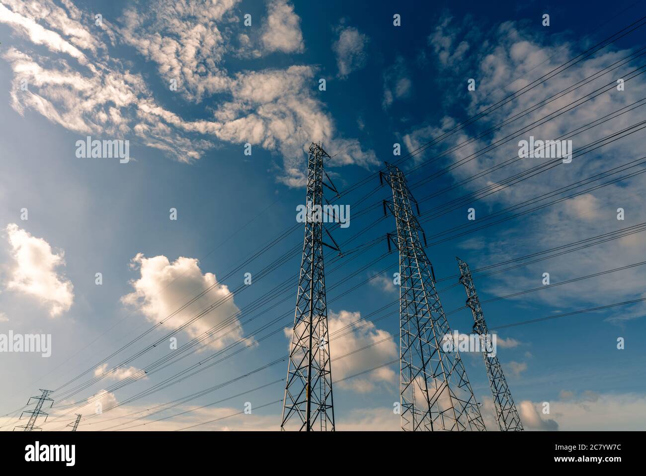 Pylône électrique haute tension et fil électrique contre le ciel bleu et les nuages blancs. Vue du bas du pylône électrique avec lumière du soleil. Grille haute tension t Banque D'Images