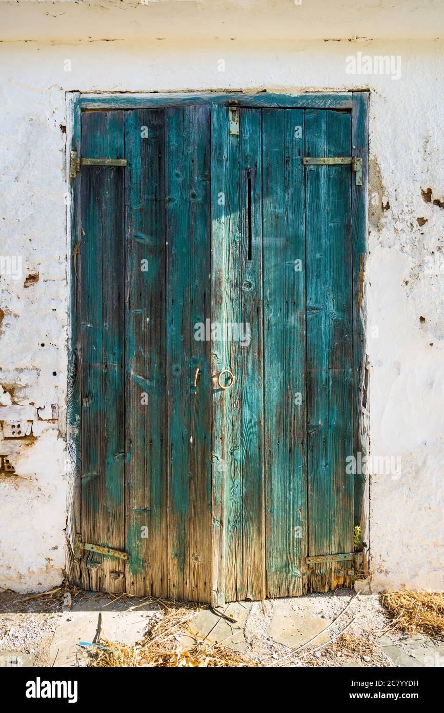 Une ancienne porte en bois turquoise d'un hangar blanc au charme vintage. Banque D'Images