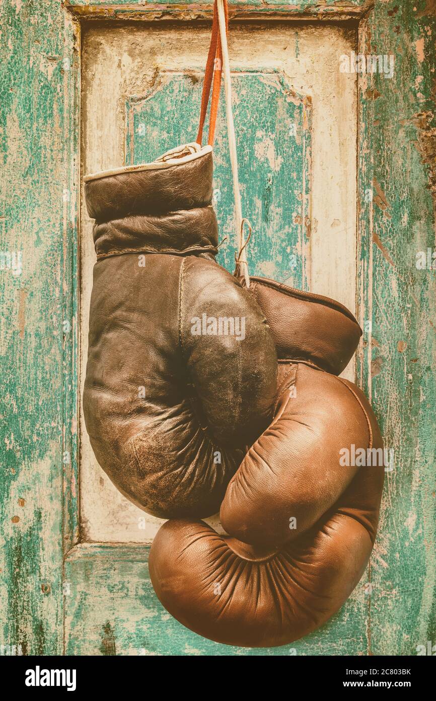 Paire de gants de boxe vintage suspendus sur une ancienne porte en bois vert vieilli Banque D'Images