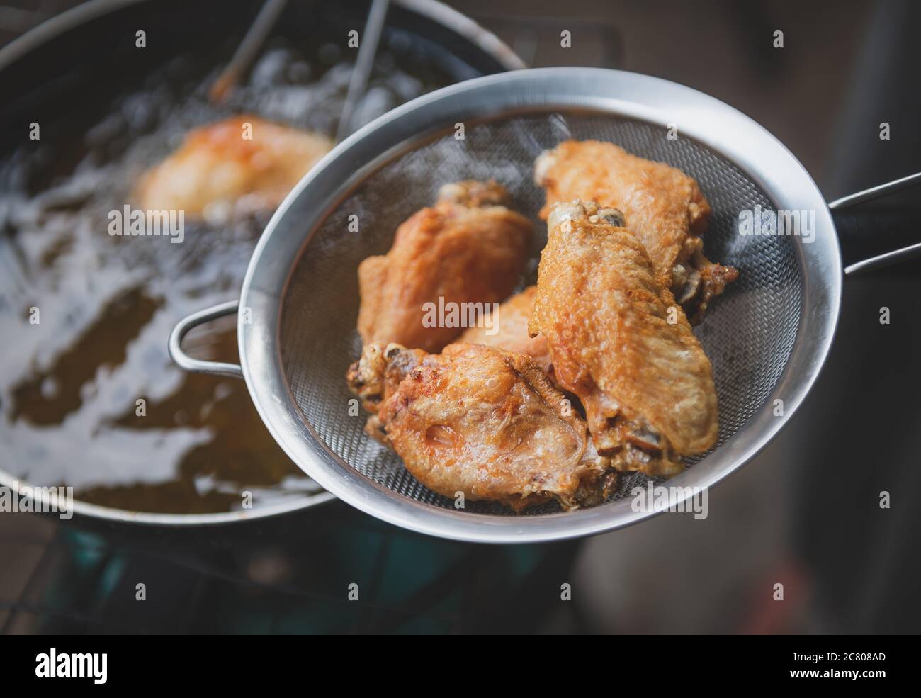 Faire frire l'aile de poulet salée avec de l'huile de cuisson dans une poêle  à repasser avec éclairage intérieur faible Photo Stock - Alamy