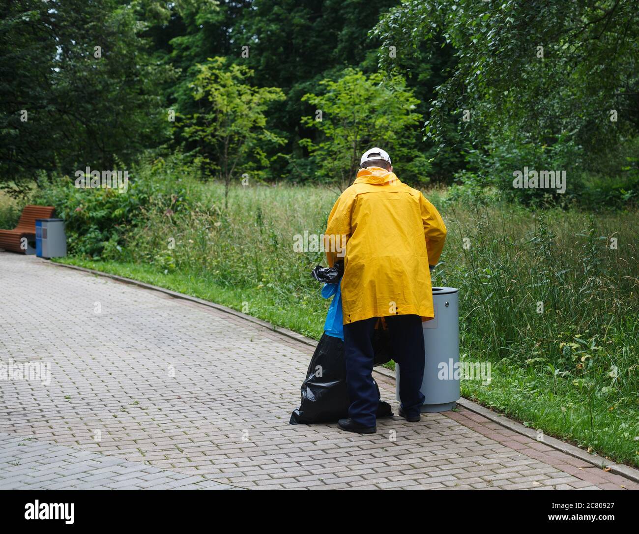 Homme avec des sacs poubelle pour trier les déchets dans un parc public. Vue arrière Banque D'Images