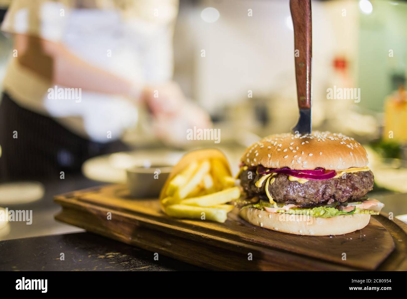 Deux délicieux hamburgers faits maison appétissants, utilisés pour hacher du bœuf. Sur la table en bois. Les hamburgers sont des couteaux insérés. Banque D'Images
