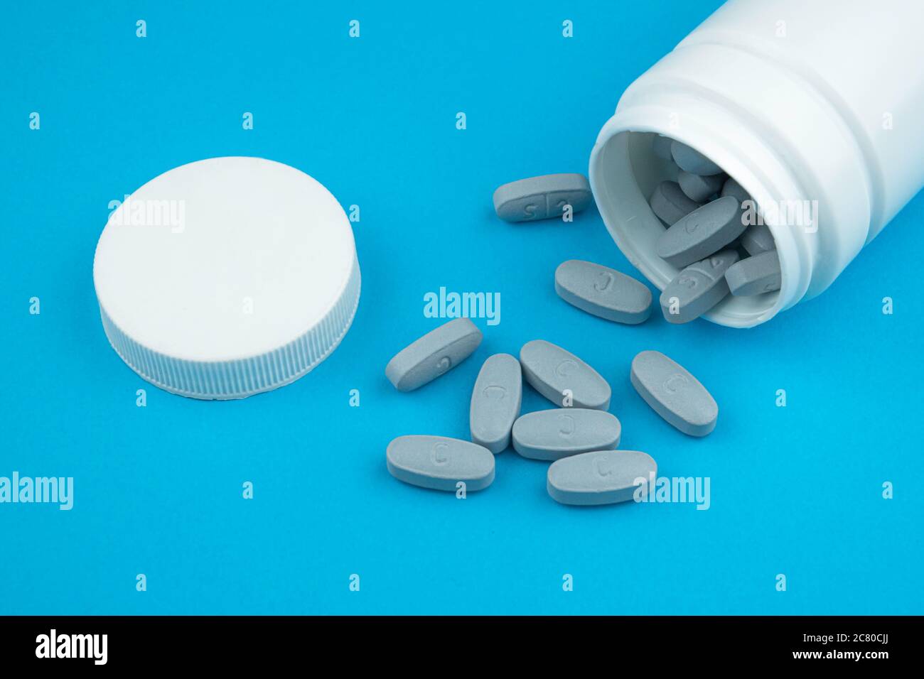 Les pilules dispersées grises et la photo de concept de bouteille de pharmacie blanche isolée sur le thème coronavirus et Covid-19. Banque D'Images