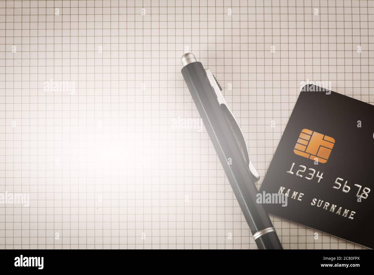 Carte de crédit noire avec stylo noir sur fond carré à motifs. Banque D'Images