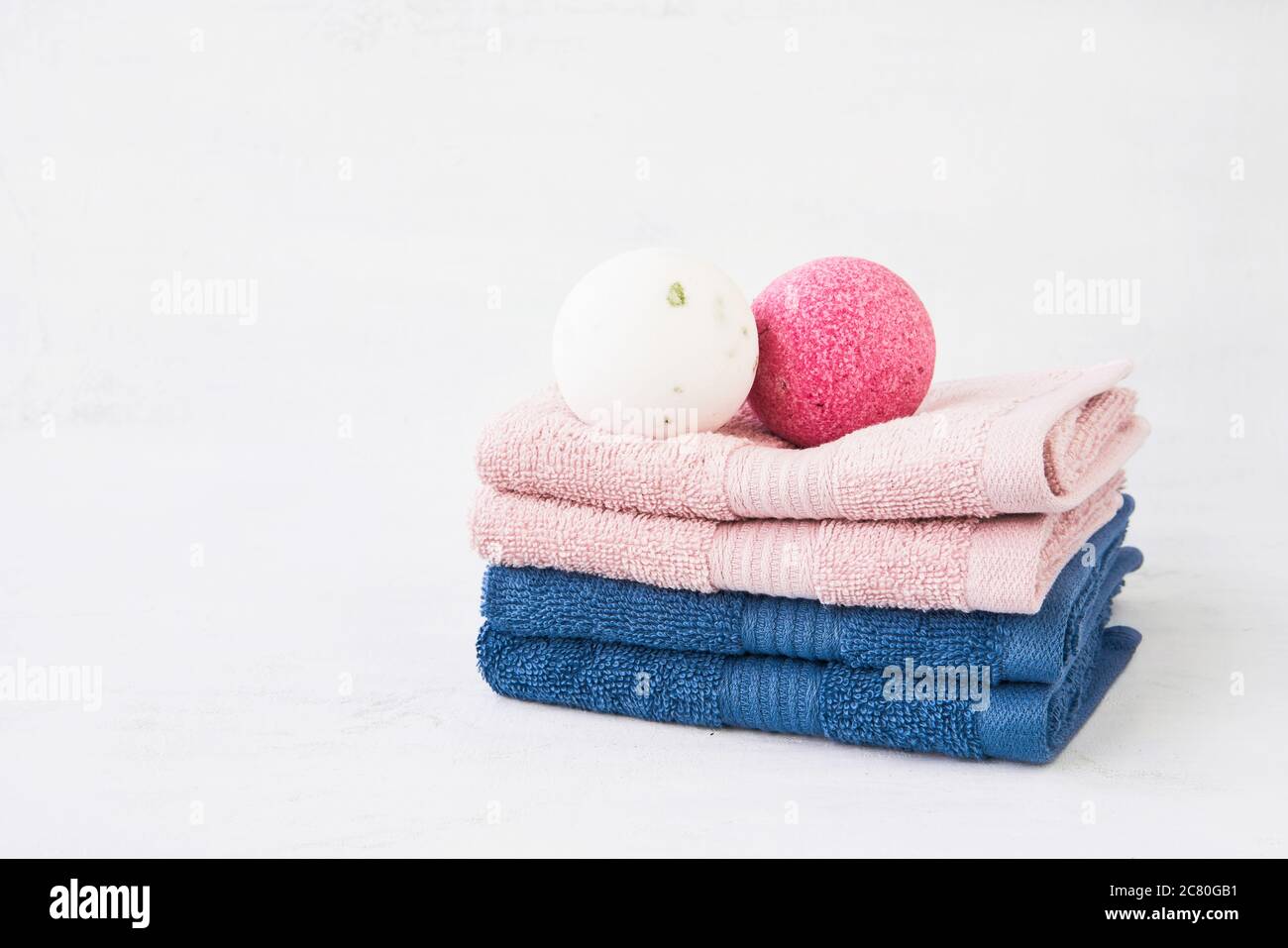 Concept SPA. Deux bombes de bain et une pile de quatre serviettes roses et bleues sur fond clair. Copier l'espace pour le texte Banque D'Images