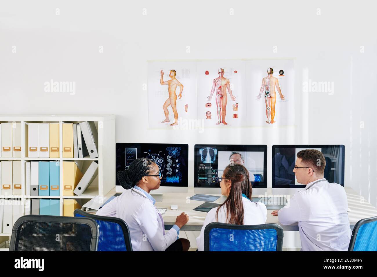 Groupe de jeunes médecins ayant une conférence en ligne avec un pneumologue expérimenté ou un spécialiste des maladies infectieuses Banque D'Images