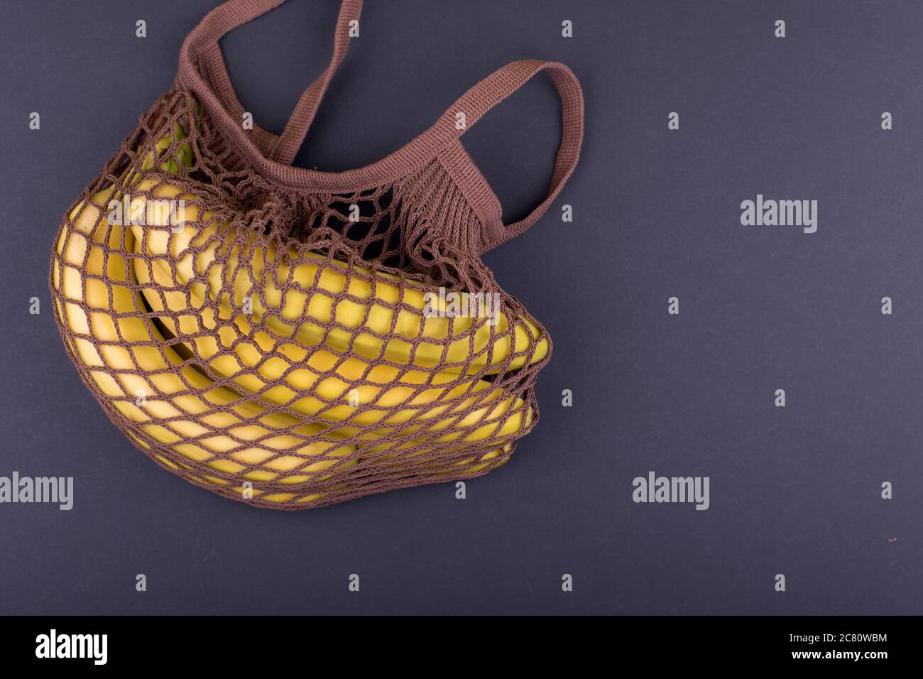 Bananes jaunes dans un sac à ficelle beige sur fond noir, espace de copie Banque D'Images