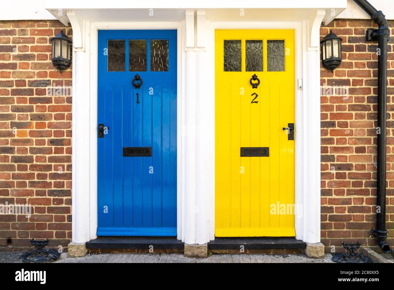 Extérieur de la maison, deux portes avant en bois et en verre. Cadre commun  avec une porte bleue et une porte jaune, numérotées 1 et 2. Les deux  identiques à l'autre Photo
