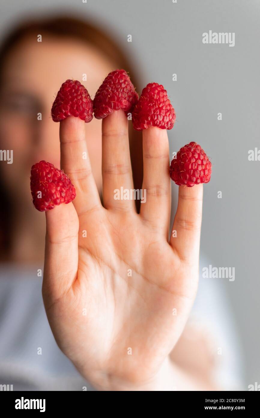 Jeune fille avec des baies de framboise sur les doigts, se concentrer sur les mains Banque D'Images