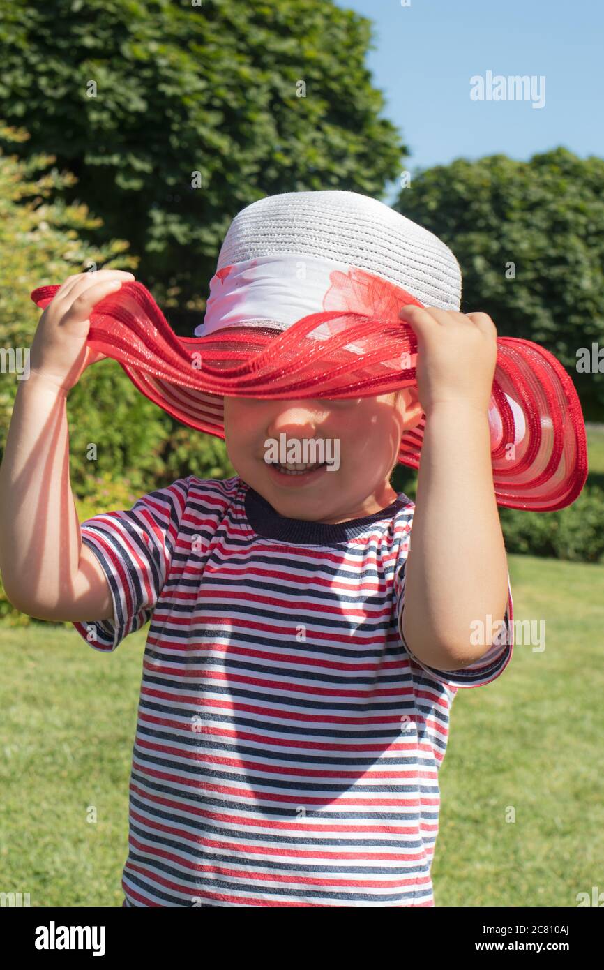 Un garçon de 3 ans dans un chapeau rouge et un t-shirt rayé. Bonne enfance  en été. Protection solaire pour enfants Photo Stock - Alamy