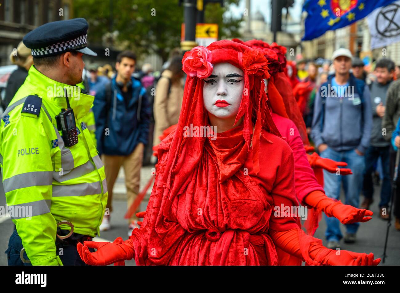 LONDRES - 18 OCTOBRE 2019 : gros plan des manifestants de la Brigade rouge de la rébellion d'extinction passant devant un officier de police métropolitain Banque D'Images