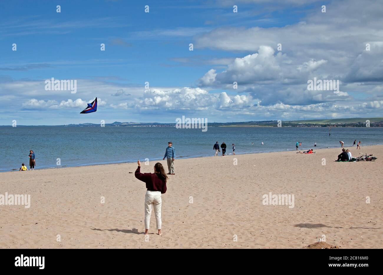 Portobello, Édimbourg, Écosse, Royaume-Uni. 20 juillet 2020. Cette jeune femme s'est amusée à voler son cerf-volant sur une plage très calme pour la mi-juillet. Soleil et cumulus avec des conditions venteuses. Vent de l'ouest 23 km/h rafales de 37 km/h température de 17 degrés. Banque D'Images