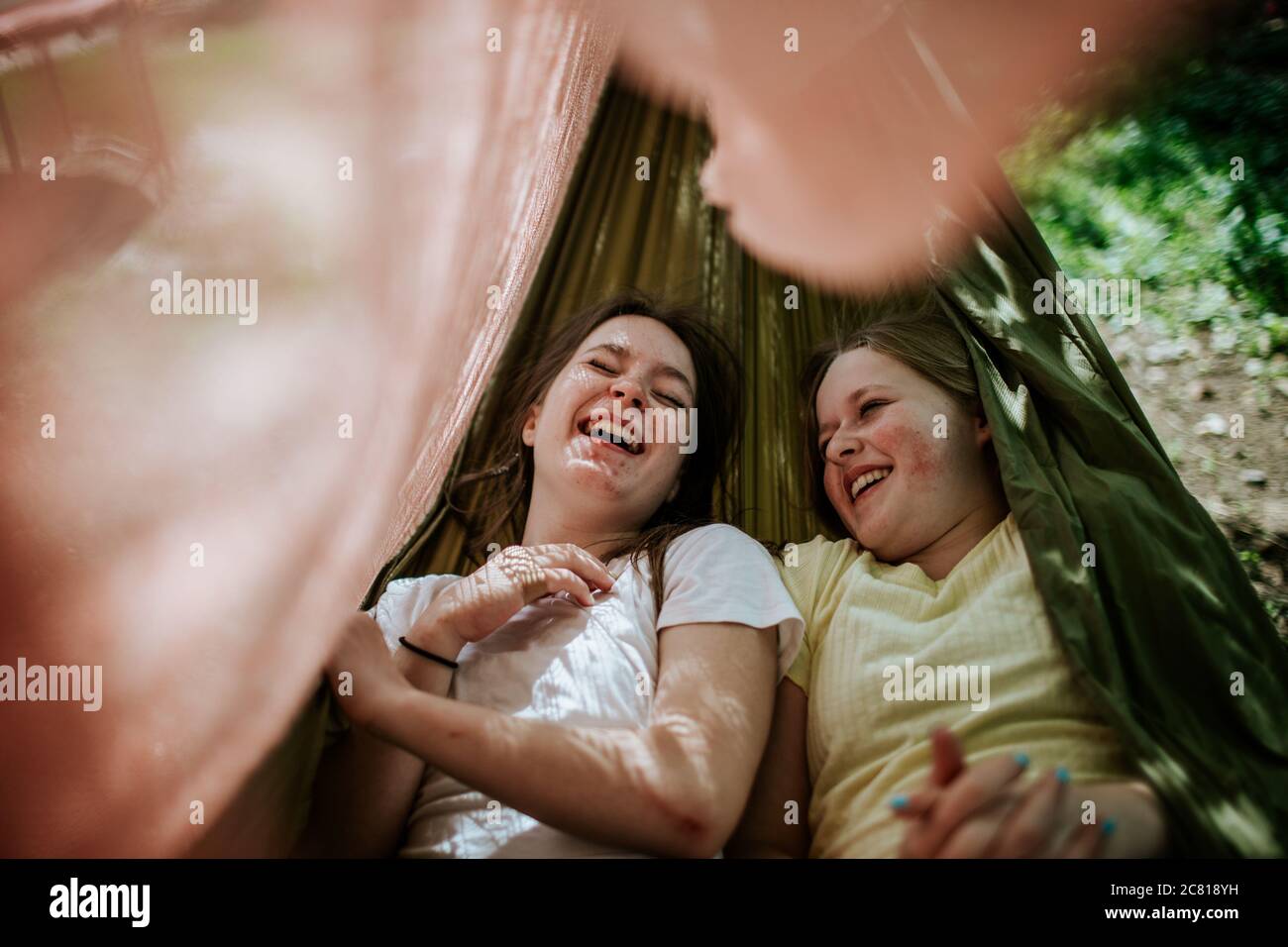Deux adolescentes qui pontent dans un hamac riant et souriant dehors Banque D'Images