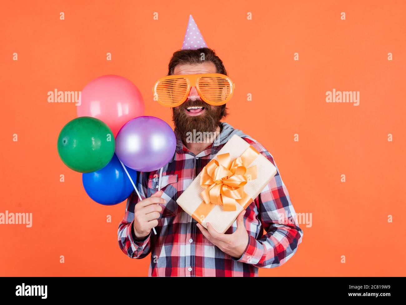 préparez-vous pour un anniversaire. responsable d'événement avec boîte cadeau. homme brutal en fête. homme drôle en chapeau d'anniversaire. joyeux noël. fête folle. amusez-vous avec des ballons. Banque D'Images