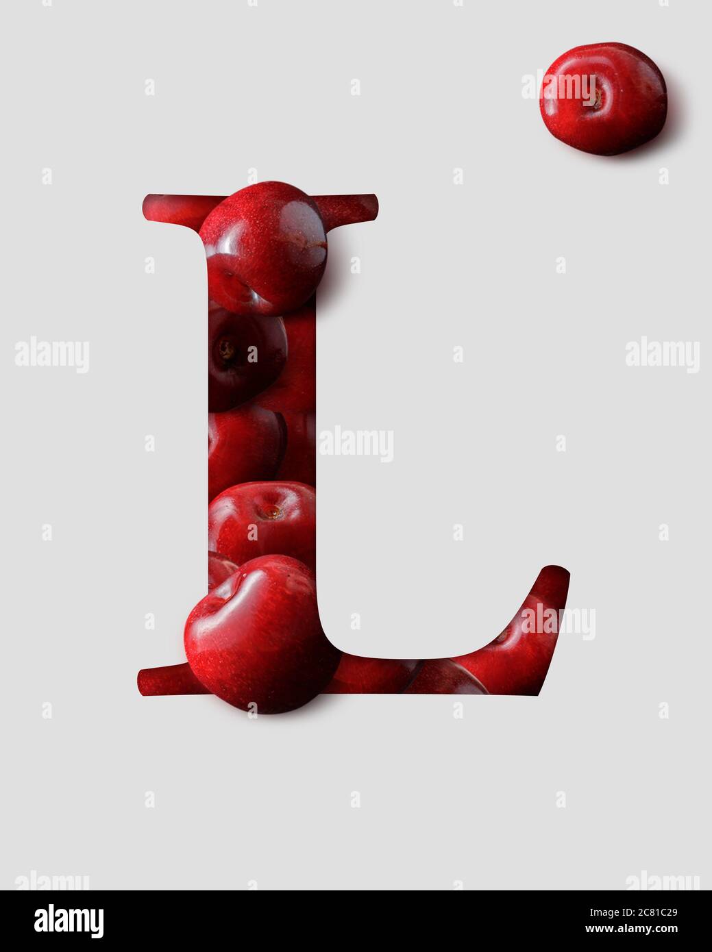 Lettre L de l'alphabet anglais créée à partir de cerises. Lettre 3D en cerisier avec ombre derrière un papier gris clair. Banque D'Images