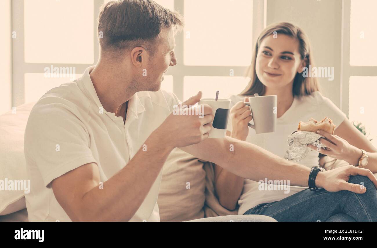 un jeune couple boit du café sur le canapé dans un nouvel appartement. Banque D'Images