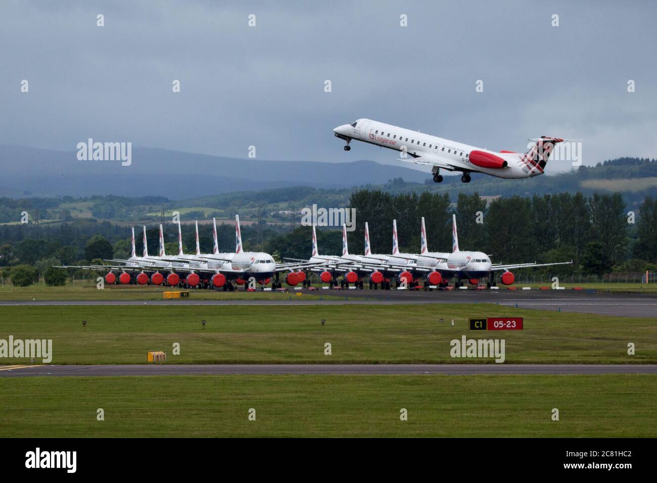 Glasgow, Écosse, Royaume-Uni. 20 juillet 2020. Photo : avion de Loganair Embraer ERJ145 vu à l'aéroport de Glasgow avec un grand groupe d'Airbus de British Airways (BA) mis au sol en arrière-plan. Loganair avait pris le contrôle de certaines des machines à sous de Flybe après l'effondrement de Flybe, puis le blocage du coronavirus a frappé en mars, et depuis, Loganair a augmenté les services, mais ce sont des temps turbulents pour toutes les compagnies aériennes et l'industrie mondiale de l'aviation. Crédit : Colin Fisher/Alay Live News Banque D'Images