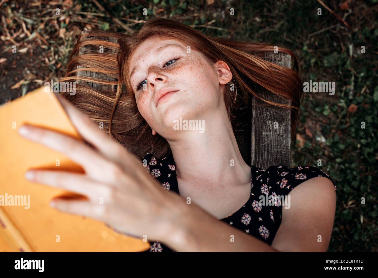 Adolescent, fille étudiante de gingembre couché sur le banc, lisant un  livre Photo Stock - Alamy