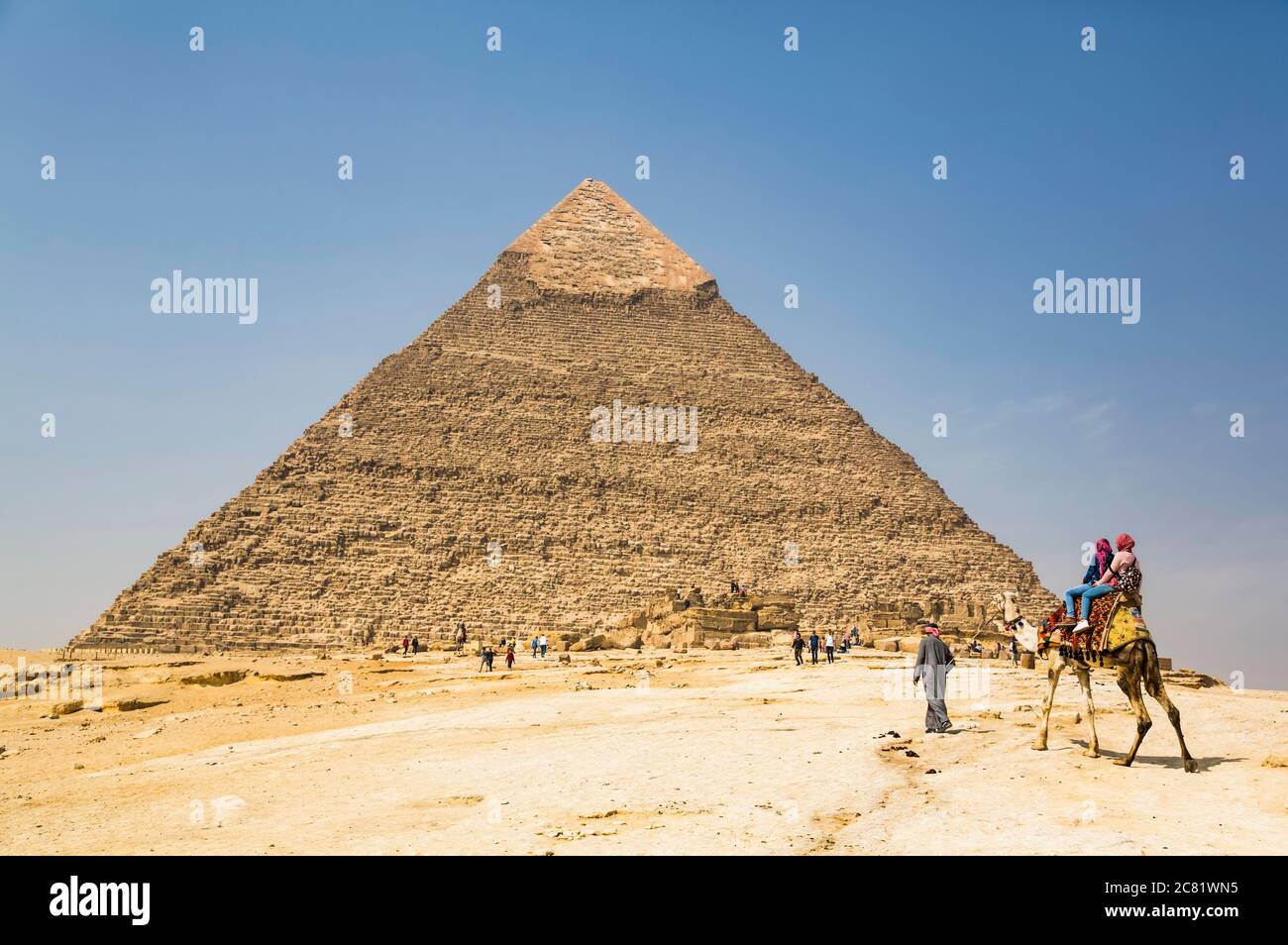 Touristes à cheval sur un chameau, Pyramide de Khafre, complexe de la pyramide de Giza, site classé au patrimoine mondial de l'UNESCO ; Giza, Egypte Banque D'Images
