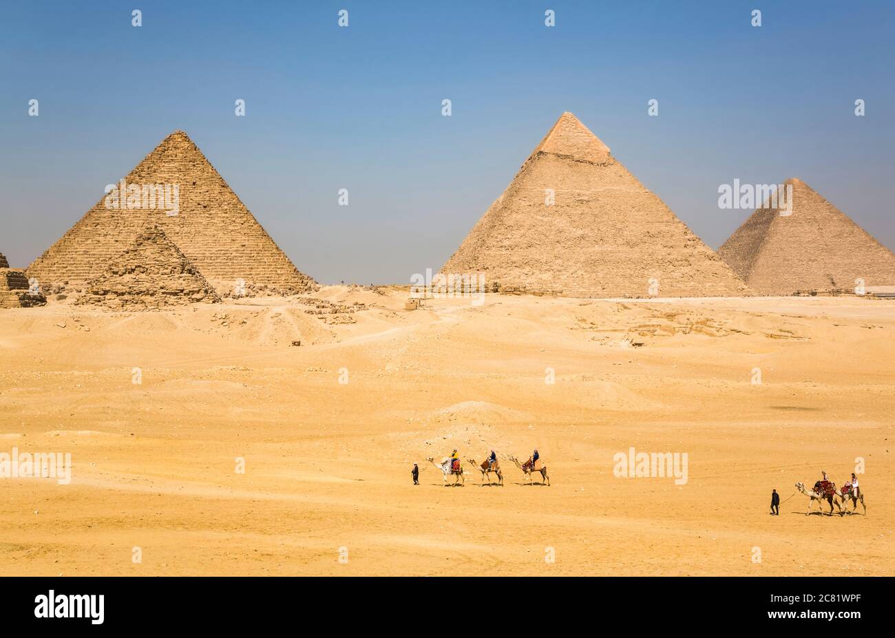 Touristes à cheval sur des chameaux, complexe de la pyramide de Giza, site classé au patrimoine mondial de l'UNESCO ; Giza, Egypte Banque D'Images