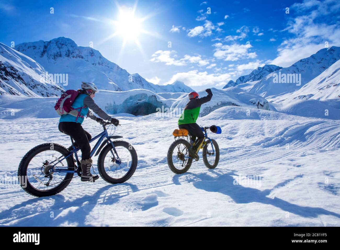 Deux femmes vélo gras en face du glacier Skookum, la forêt nationale de Chugach, en Alaska, un jour d'hiver ensoleillé, la poing pompant comme elle passe par, le sud-cente... Banque D'Images