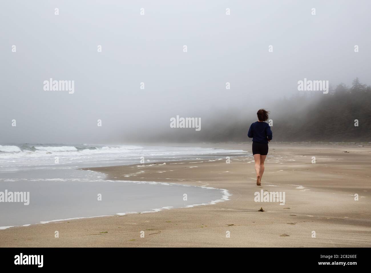 Athlétique caucasienne fille courir sur une plage de sable près de la côte de l'océan Pacifique Banque D'Images