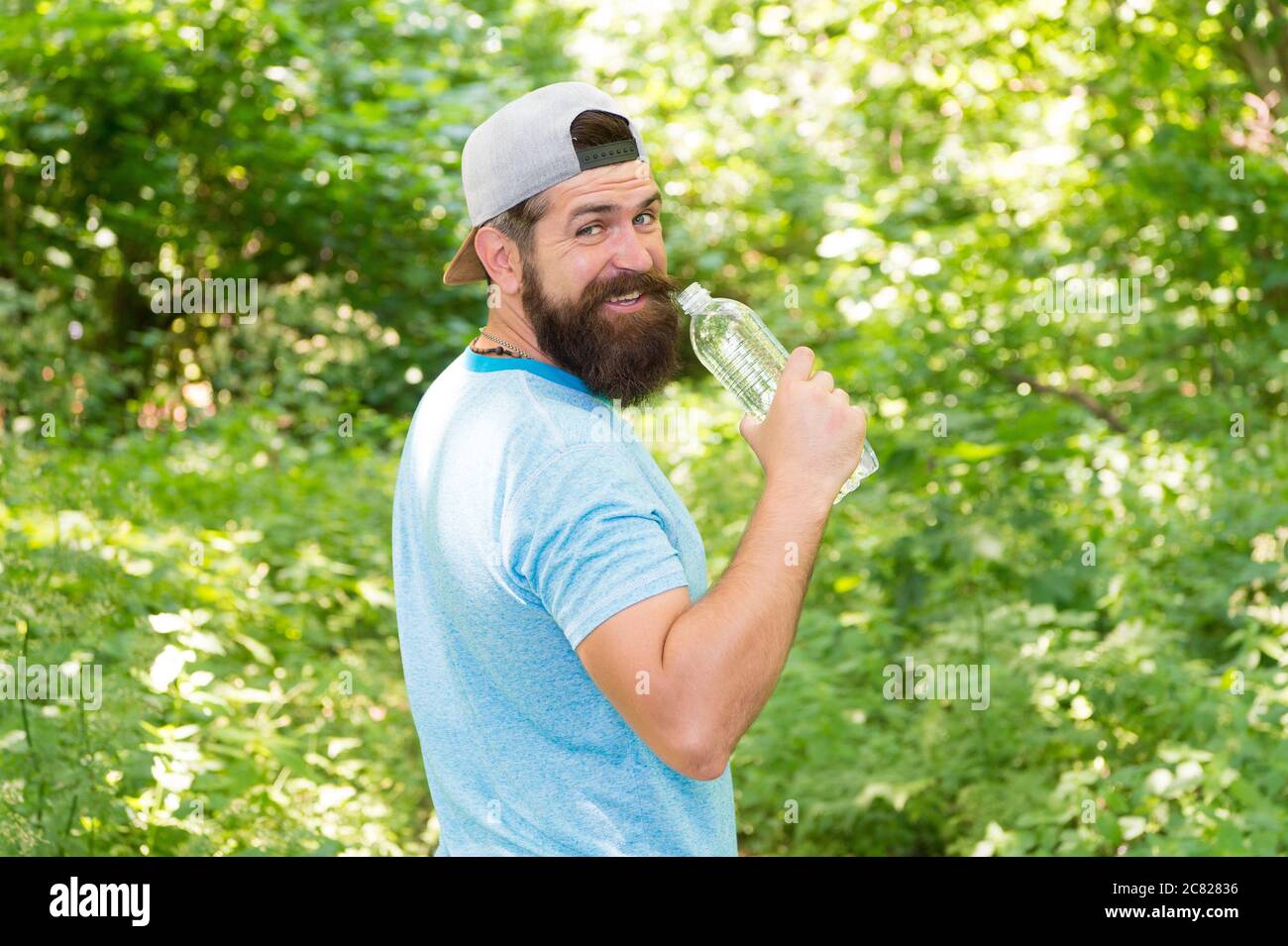 Hydrate ou mourir. Hipster brutal en forêt. Découvrez de nouveaux endroits. Temps pour pique-niquer. Guy boit de l'eau. Homme barbu en cap. Vacances d'été en camping. Homme randonnée. Homme envie d'avoir soif. Banque D'Images