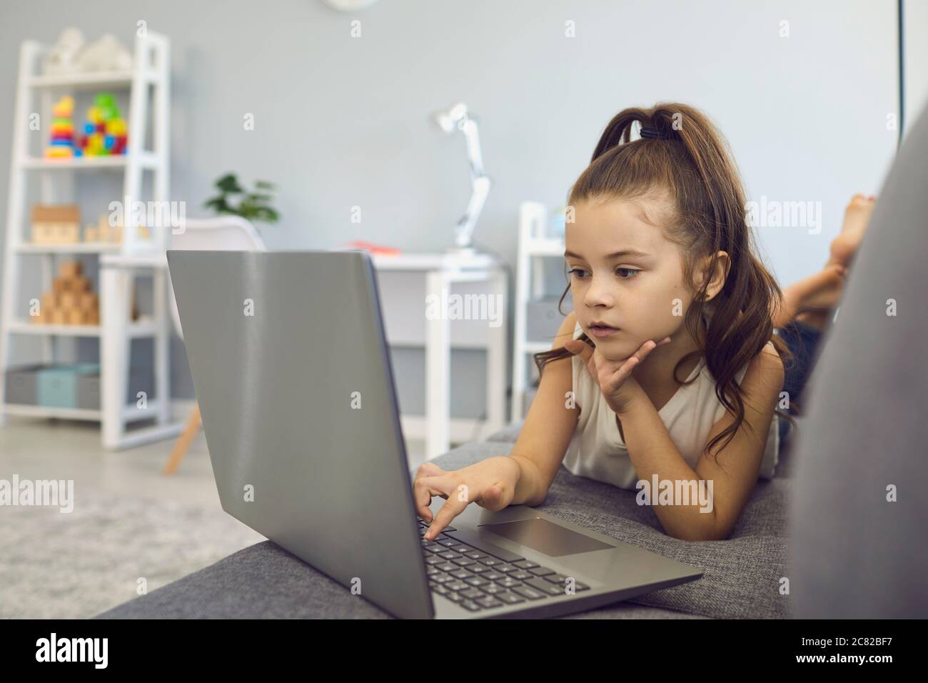 Enseignement à distance. Petite fille utilisant un ordinateur portable pour la classe en ligne à la maison. Un adorable enfant regarde des vidéos éducatives sur le Web Banque D'Images