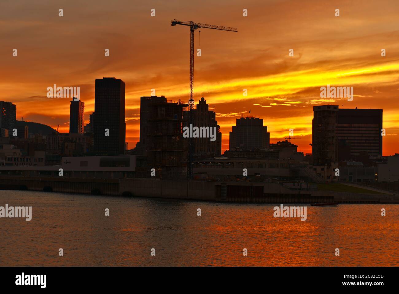 Vue sur la ville avec une grue dans un chantier de construction au milieu et en premier plan sur une rivière, le centre-ville de Montréal et la rivière Saint-Laurent Banque D'Images