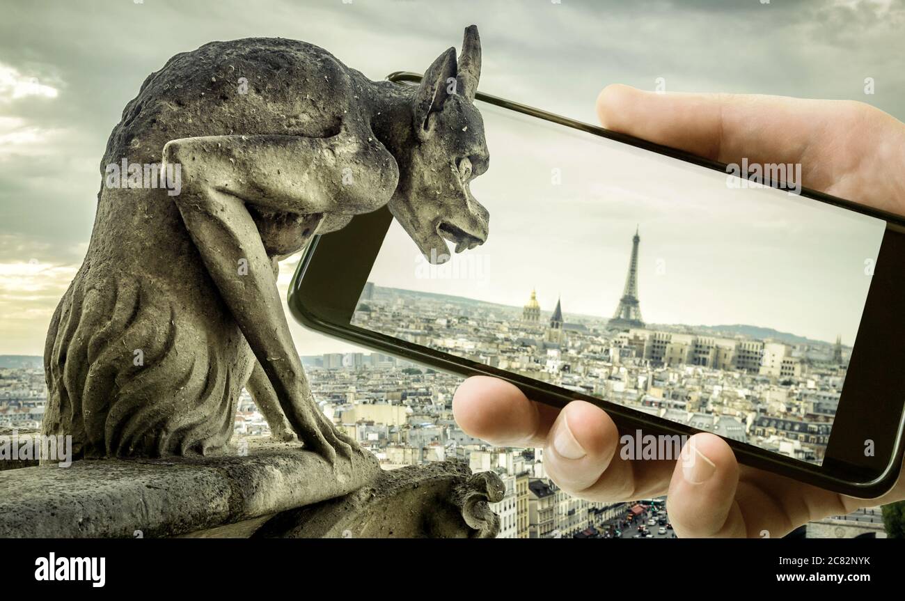 Gargoyle, sur la cathédrale notre-Dame de Paris, regarde la Tour Eiffel en mobile ou téléphone portable, Paris, France. Photo amusante de l'ancien Paris et smartphone. Co Banque D'Images