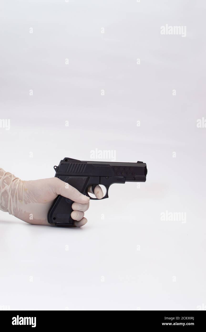 Gros plan d'une main dans un gant médical tenant Une arme à feu pendant la pandémie de Covid-19 Banque D'Images