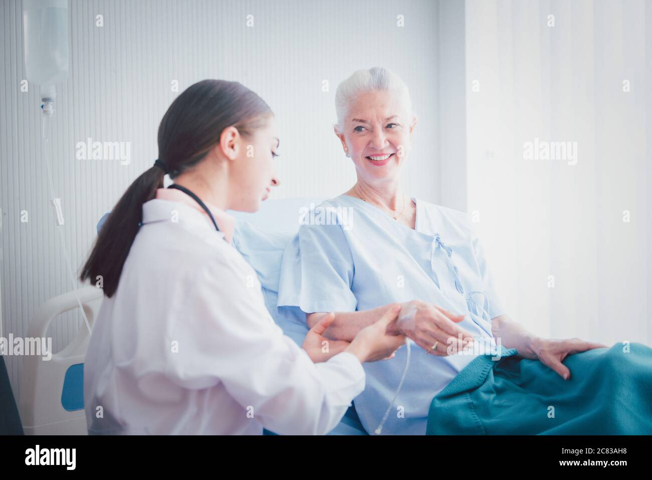 Une patiente âgée heureuse parle avec une femme médecin dans la chambre de l'hôpital. Concept de soins à domicile Banque D'Images