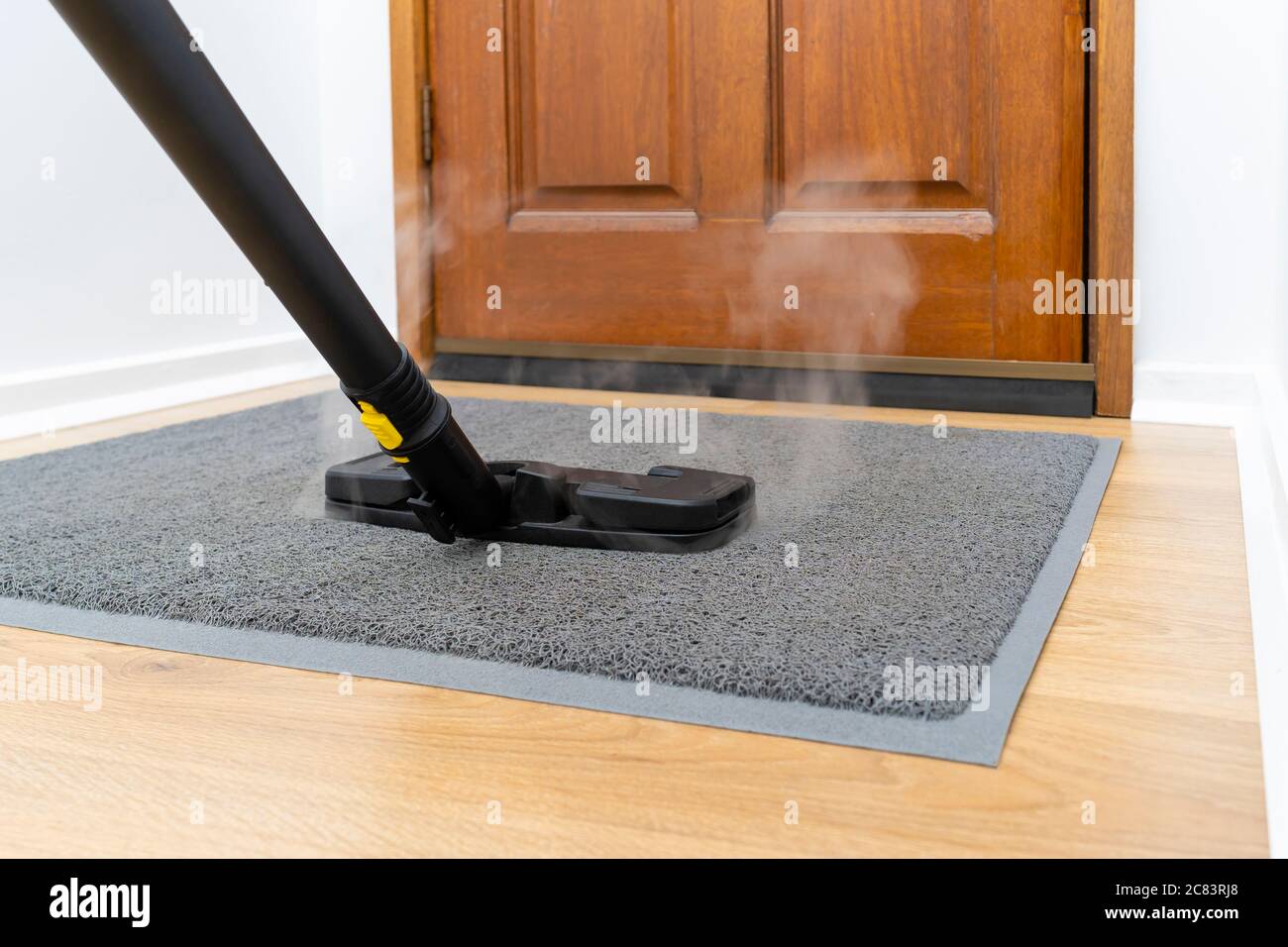 Assainir le tapis de porte avant à l'aide d'un nettoyeur vapeur Banque D'Images