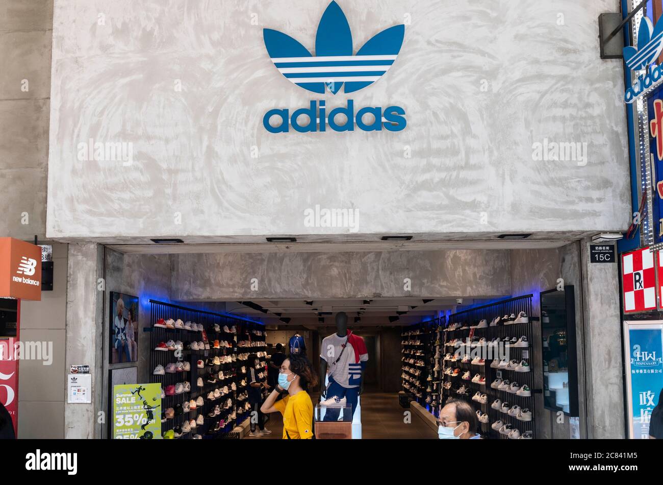 Hong Kong, Chine. 17 juillet 2020. Les piétons portant des masques de visage marchent devant une marque allemande multinationale de vêtements de sport Adidas magasin et logo vu à Hong Kong. Crédit : SOPA Images Limited/Alamy Live News Banque D'Images
